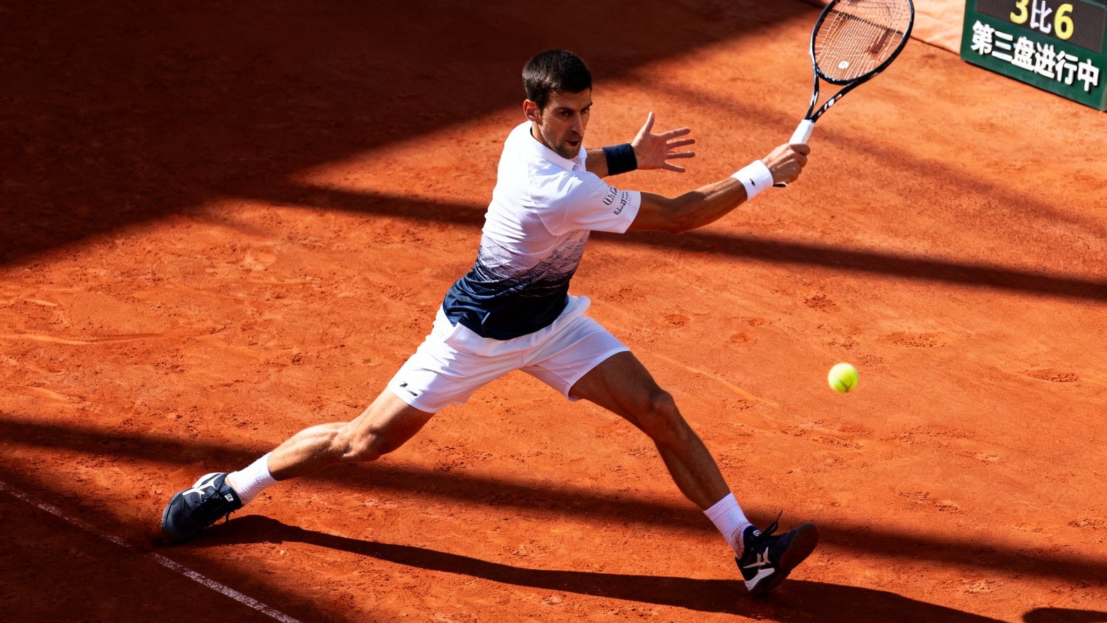 德约科维奇在ATP网球巡回赛中的高清直播画面，红土场地上球员正全力挥拍击球，阳光洒在球场上形成明暗交错的光影，比分牌显示当前盘分6比4和3比6，第三盘正在进行中。